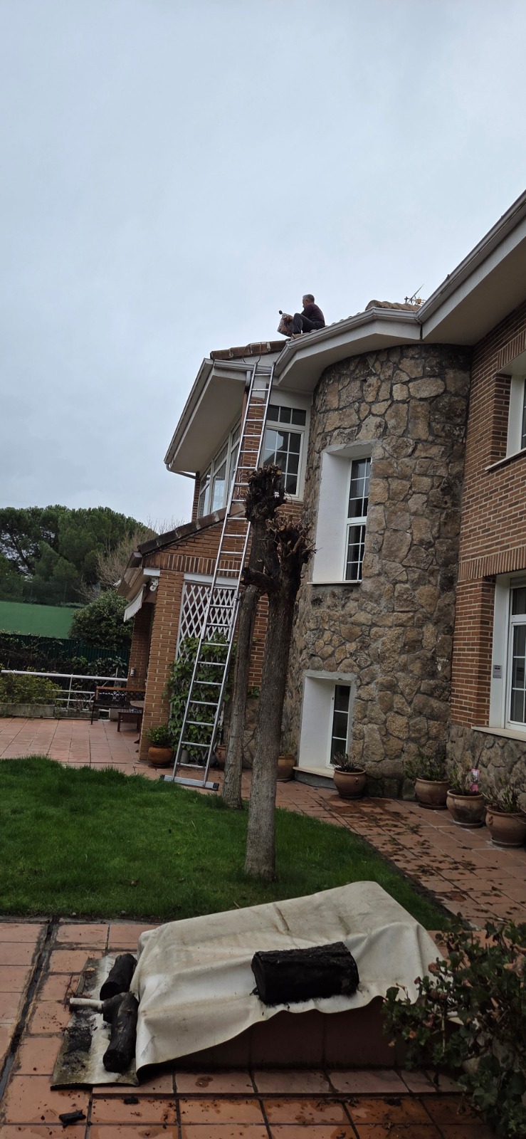 The man on top of the roof cleaning the guttering